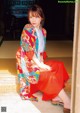 A woman in a colorful kimono sitting on the floor.