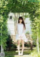 A woman in a white dress standing on a wooden bench.