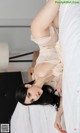 A woman laying on top of a bed in a white lingerie.