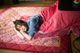 A young girl laying on a bed covered in a blanket.