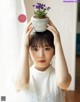 A woman holding a potted plant on top of her head.