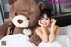 A woman laying in bed next to a large teddy bear.