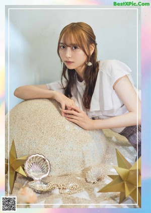 A woman sitting on top of a large rock next to a star.