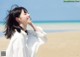 A woman standing on a beach with her hair blowing in the wind.