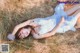 A woman laying in a field of tall grass.