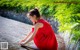 A woman in a red dress crouching down on the ground.