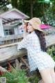 A woman in a blue and white checkered shirt and a straw hat.