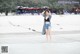 A woman standing in the water on a beach.