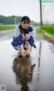 A woman crouching down in a puddle of water.